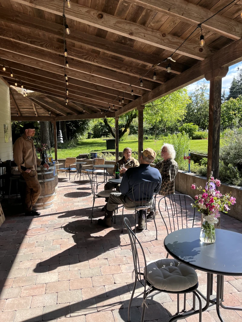 A group of people sitting at a table on the patio at Shawnee Hill Farm tasting room.