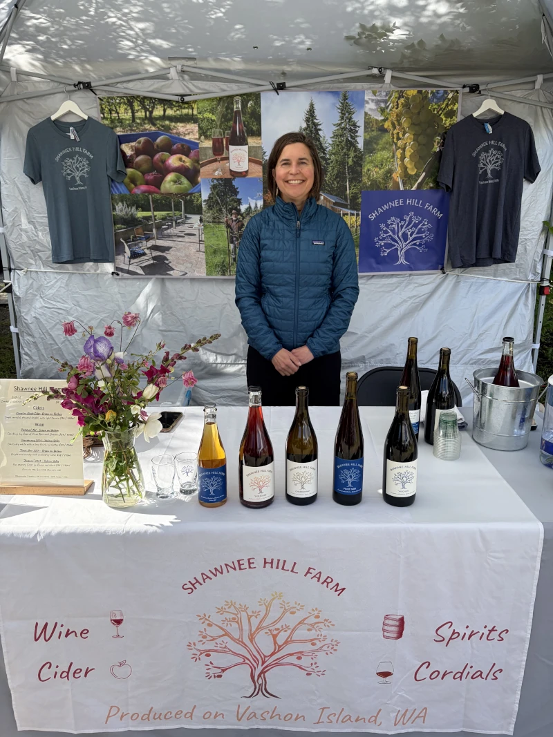A member of the Shawnee Hill Farm team standing behind a table at a farmer's market.
